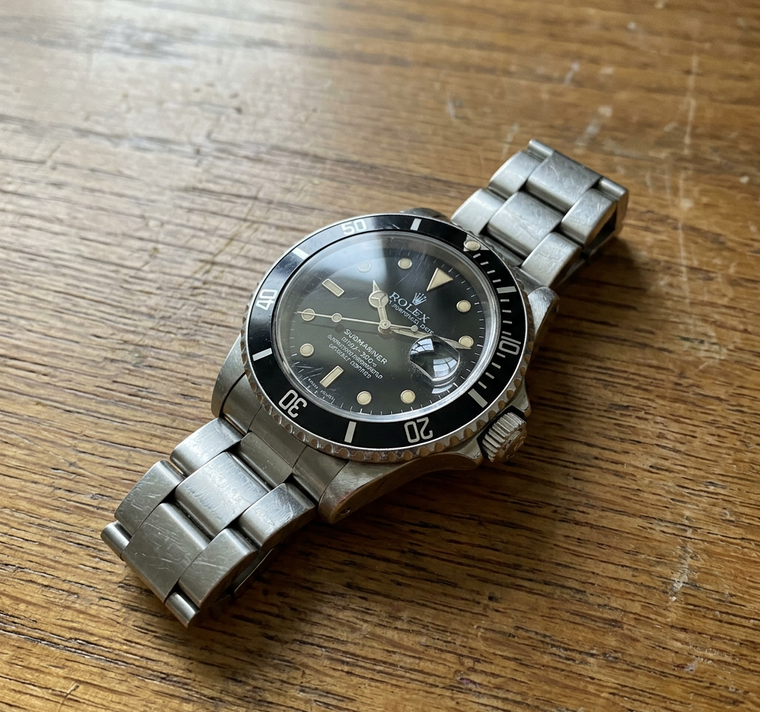 A raw, unedited phone photo of a wristwatch on a wooden desk — before Relio's AI processes it